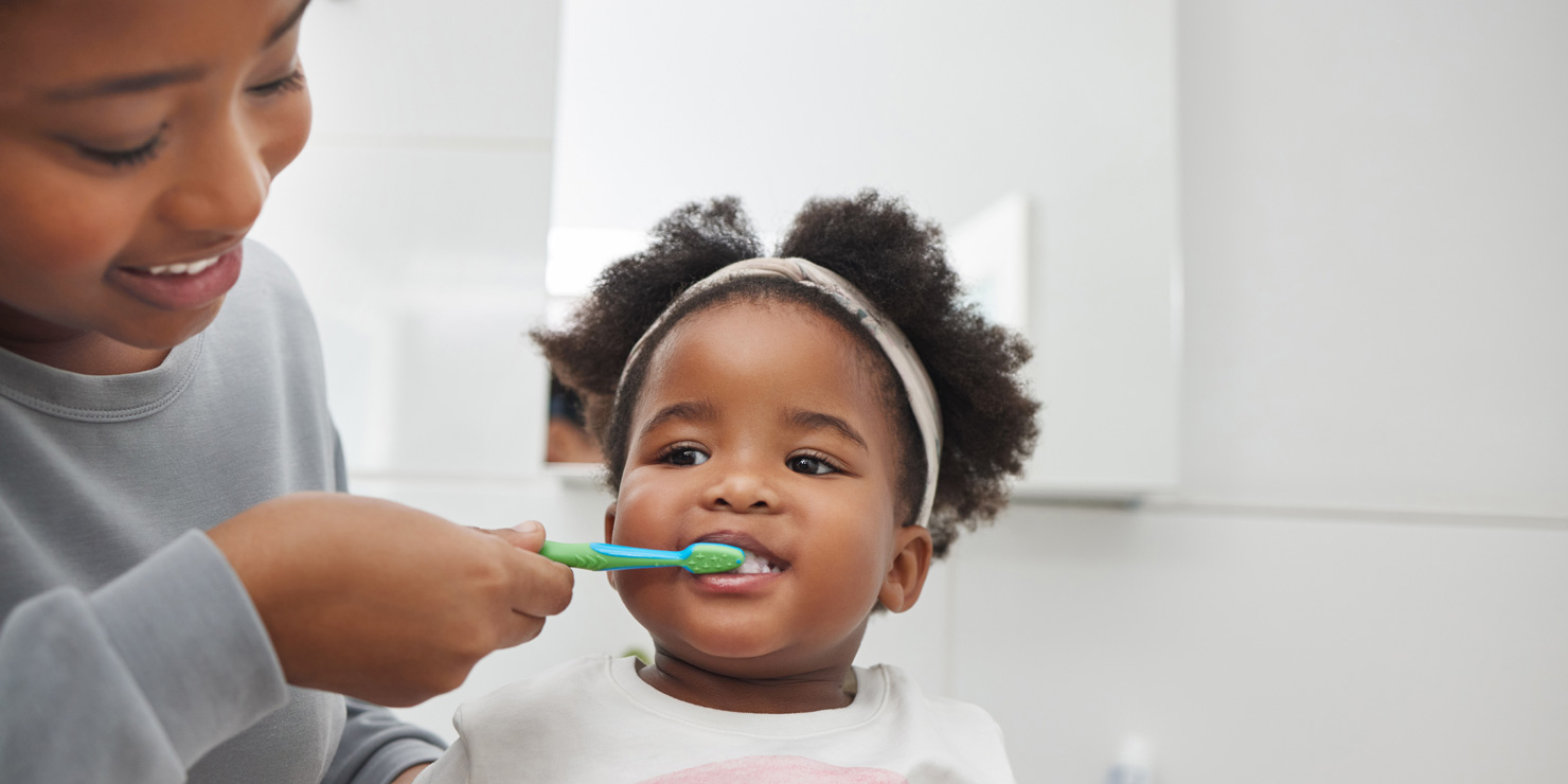 mother brushing her little daughters teeth