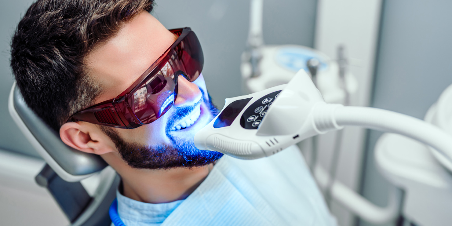 Dentist starting teeth whitening procedure